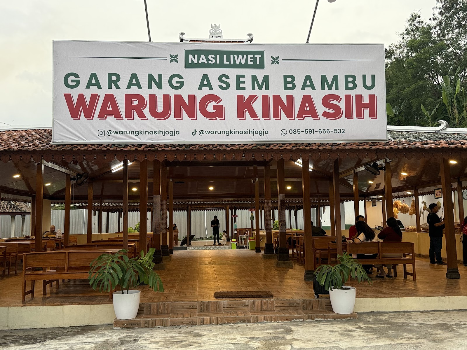 Plang Warung Kinasih di depan pendopo dengan nomor WhatsApp dan akun media sosial